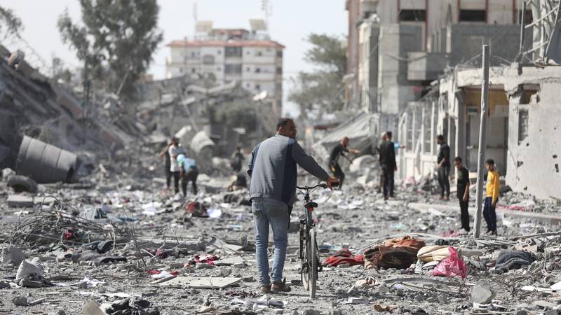 Palestinians walk by the buildings destroyed in the Israeli bombardment on al-Zahra, on the...