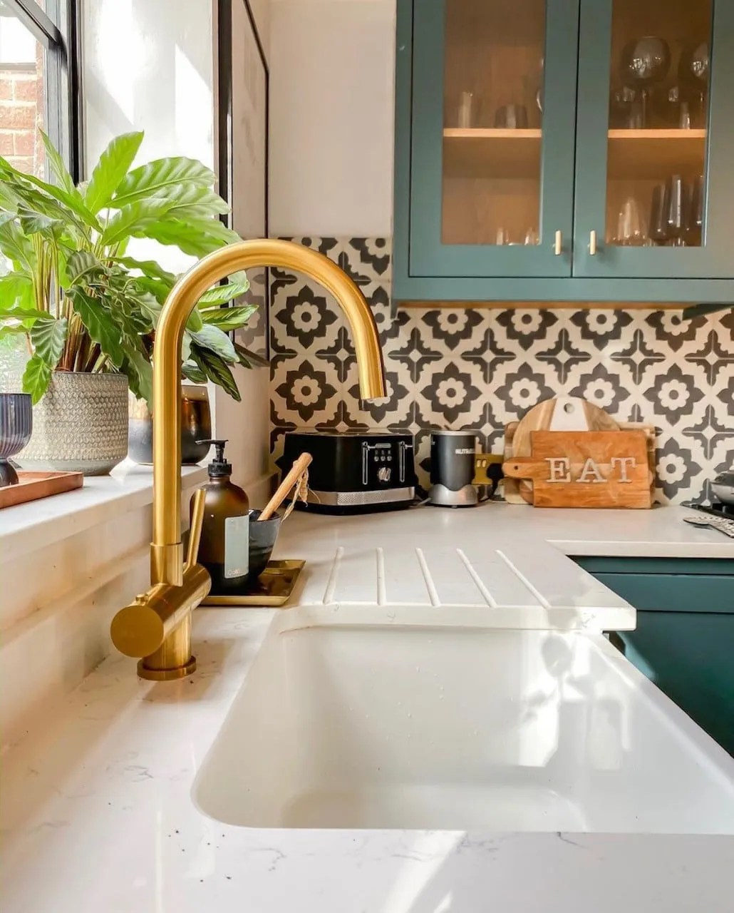 monochrome tiles in the kitchen with green kitchen cabinets and gold taps