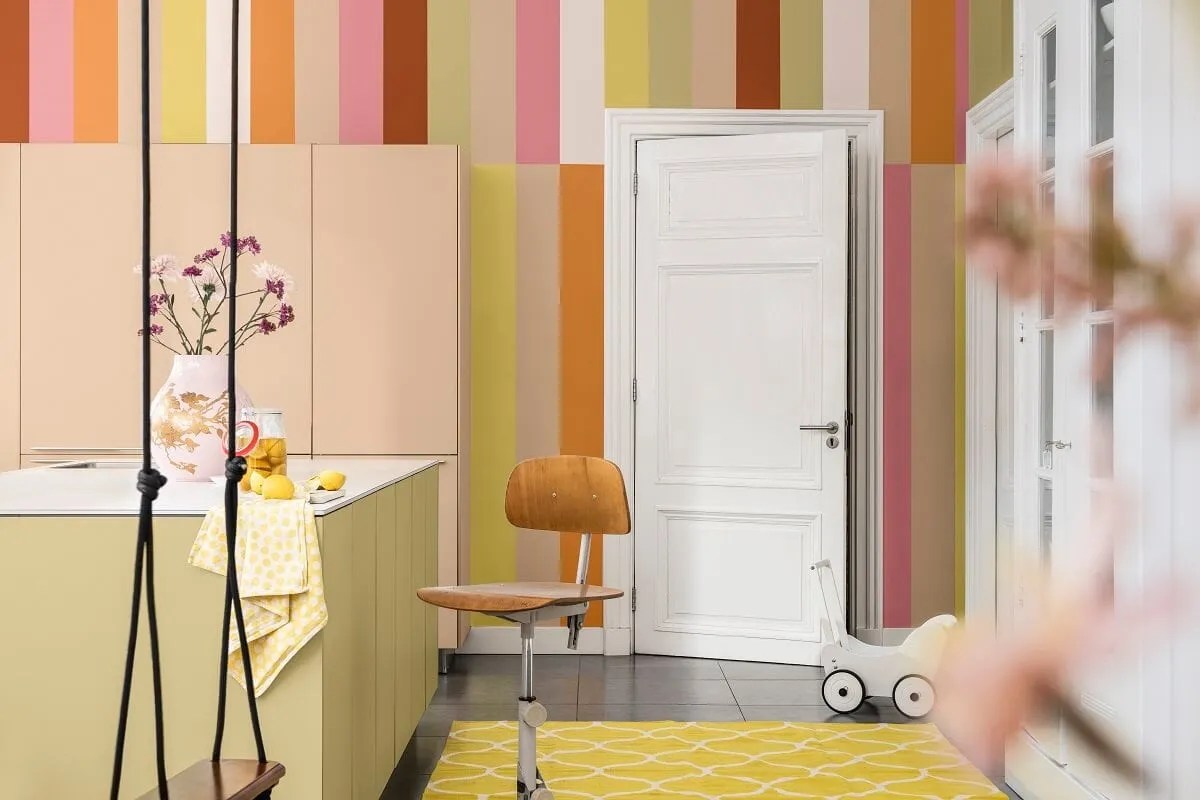 kitchen painted in yellows, pinks and oranges in stripes with a wild wonder painted island