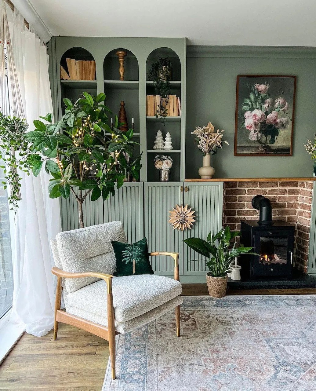 green IKEA units in the living room with books and ornaments. There is a biofuel burner in the middle and a boucle chair