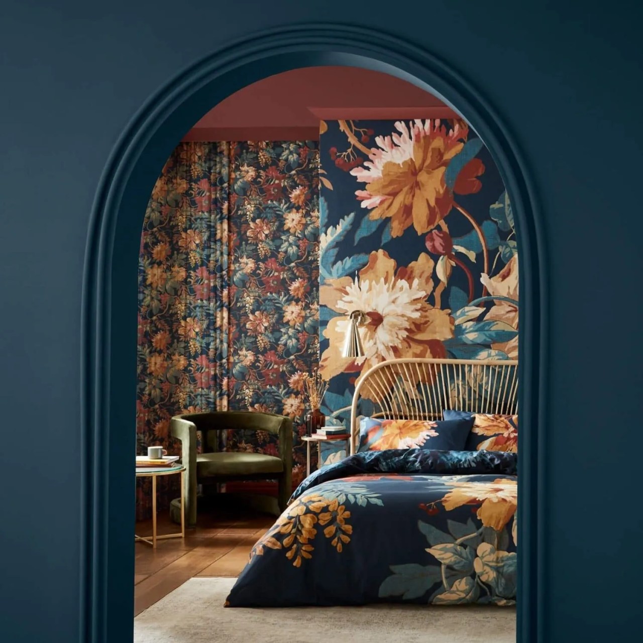 dark blue archway into the bedroom with Graham and Brown's Florenzia Dusk wallpaper and cane bed