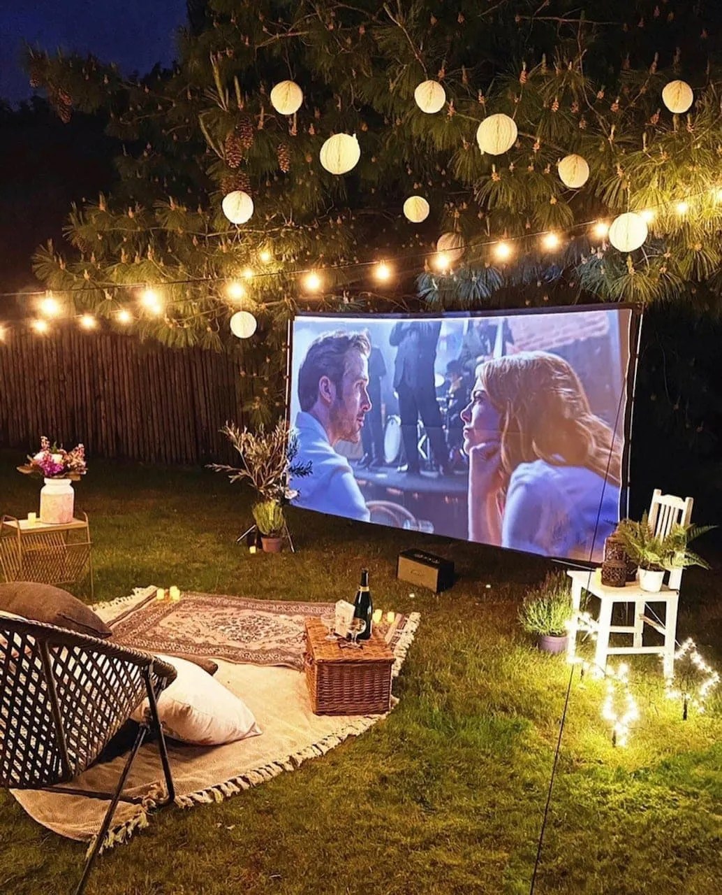 outdoor movie night with lanterns and string lights in the garden