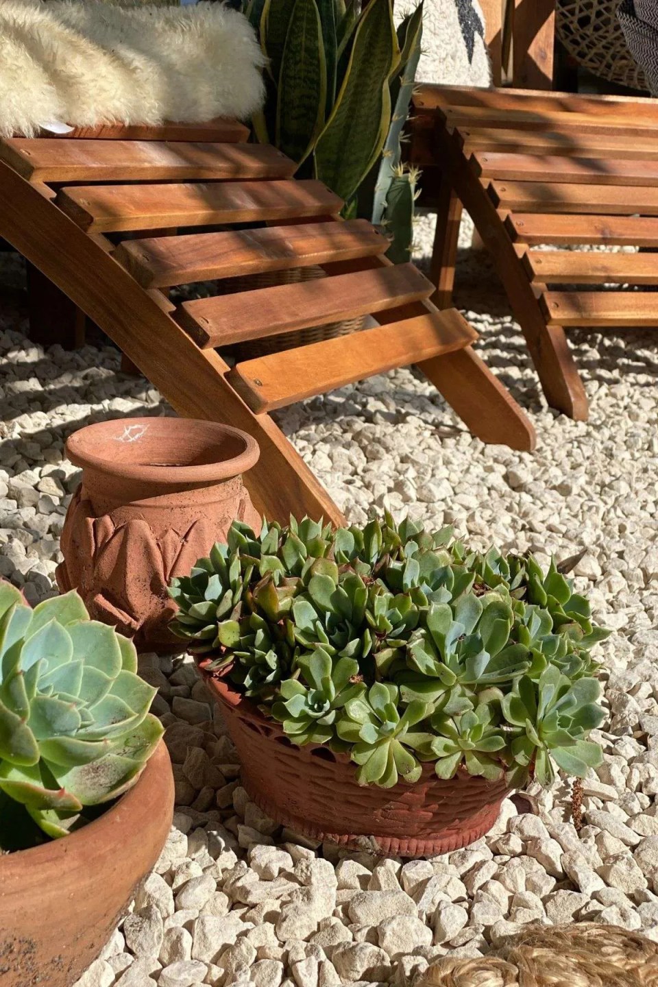 white gravel in a garden with adirondack chairs and terracotta pots