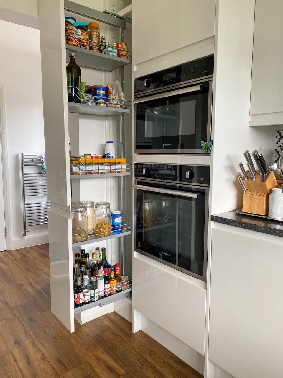 a pull out pantry in the kitchen filled with spices