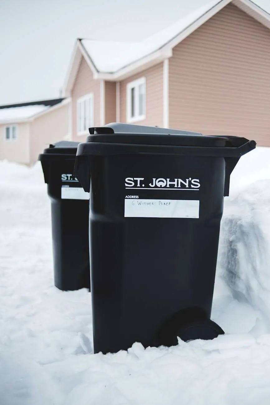 similar rubbish bins on snow near house facade in town