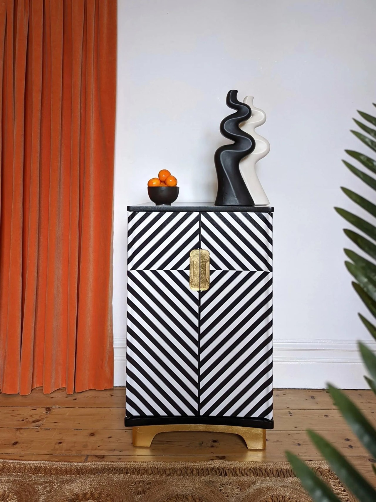 Black and white diagonal striped drinks cabinet with gold fittings