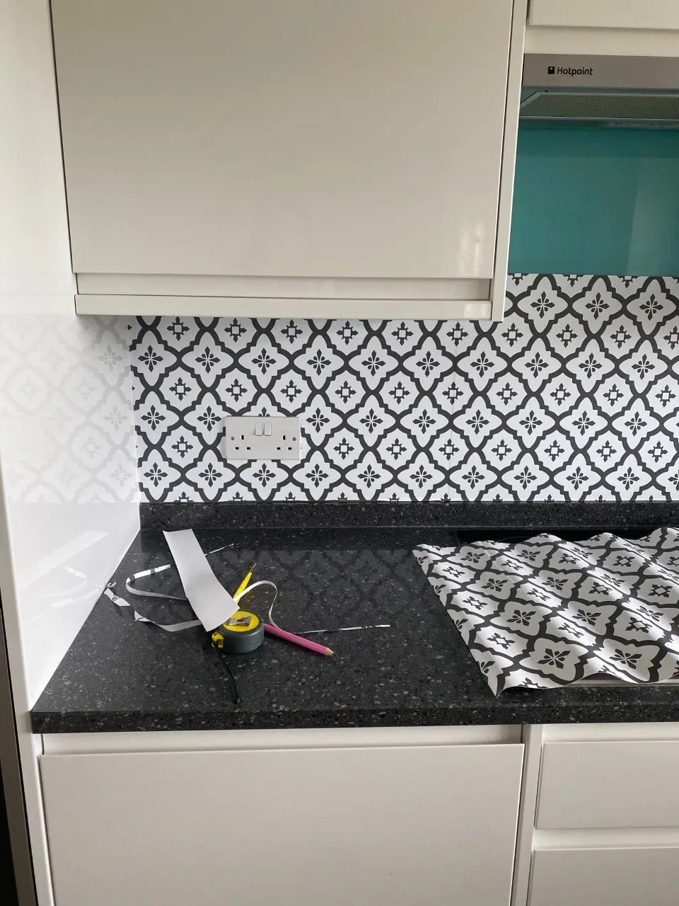 peel and stick tiles going up over the glass tile in the kitchen